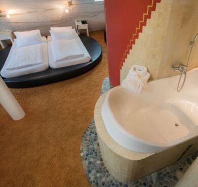 Zimmer mit Doppelbett in runder Form und Badewanne.