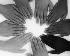 Viele verschiedene Hände von Menschen mit unterschiedlicher Hautfarbe treffen sich zu einem Kreis.