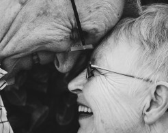 Ein älteres Ehepaar legt den Kopf vertrauensvoll aneinander.
