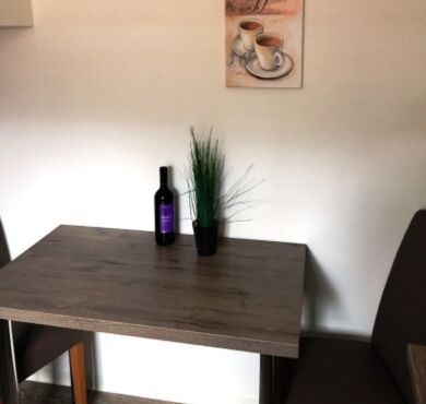 Tisch mit zwei Stühlen und einer Weinflasche.