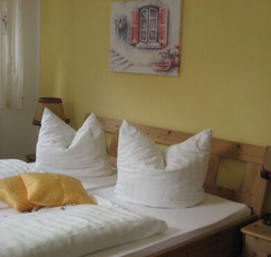 Altstadthotel Schex Altötting, Foto Jehle Doppelbett vor gelber Wand.