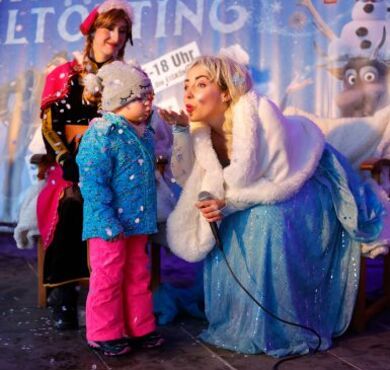 Elsa die Eiskönigin pustst Glitzerstaub von ihrer Hand.