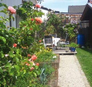 Garten mit Rosen und Terrasse mit Tisch und Stühlen