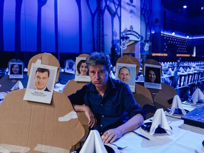 Richard Oehmann, Zukunftsforum, Forum, Altoetting, Derbleckereien, Foto Jan Saurer, Monacoshots Ein Mann sitzt an einem Tisch.