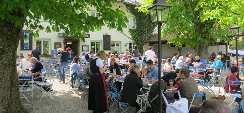 Biergarten mit vielen Menschen unter Kastanienbäumen. 