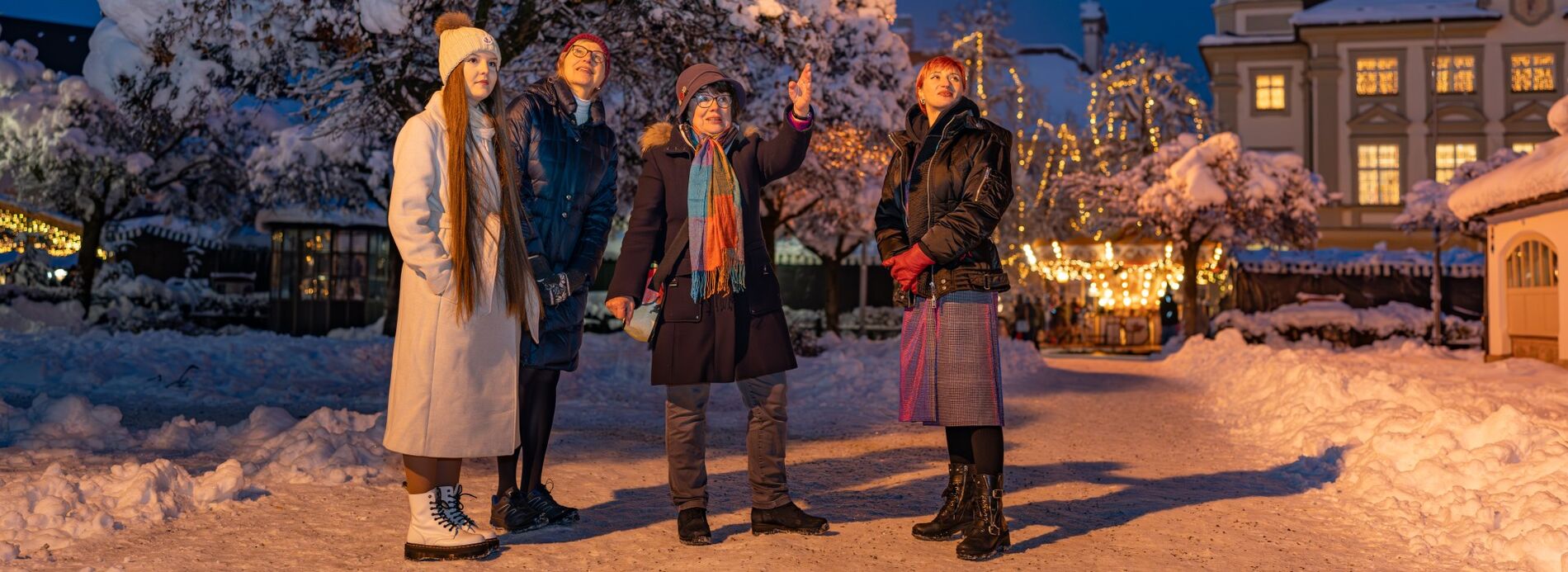 Vier Damen stehen am verschneiten Christkindlmarkt.