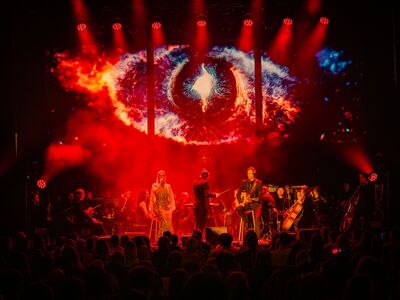 Herr der Ringe, KULTUR+KONGRESS FORUM ALTÖTTING, Foto Star Entertainment, Lancelot Productions Ein Orchester steht vor einer Lichtprojektion.