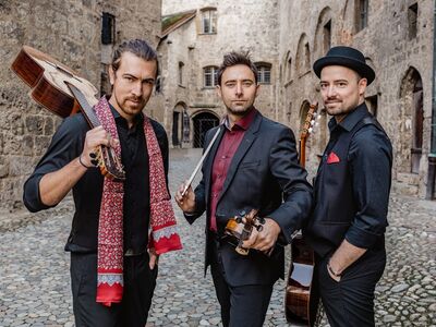 Drei Männer mit Instrumenten in der Hand stehen auf einer Straße.