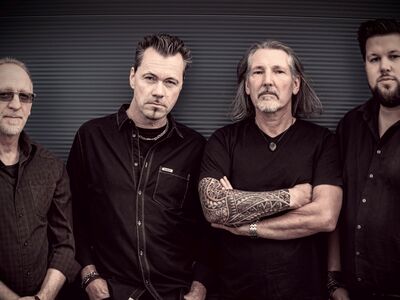 Rebel Monster, Volbeat, Forum Altötting, Bild Band Vier Männer in schwarzen Shirts stehen vor einer grauen Wand.