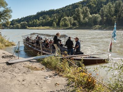 Menschen auf einem Boot am Flussufer.