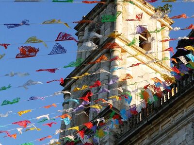 Blick auf einen Turm, vor dem viele bunte Girlanden hängen.