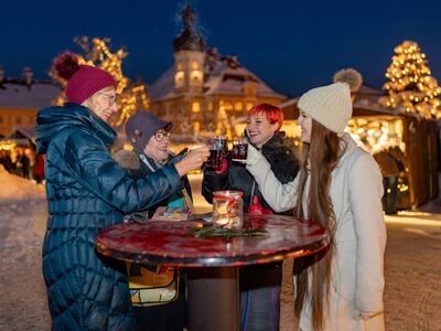 Vier Frauen stoßen mit einem Glühwein am Christkindlmarkt an.