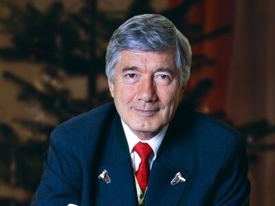 Die alpenländiche Weihnacht, Forum Altötting, Christian Wolff, Regensburger Domspatzen, Bild Preisinger Ein Herr im dunklen Anzug vor einem Weihnachtsbaum.