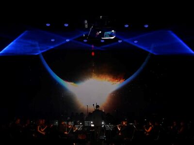 The Music of Hans Zimmer, KULTUR+KONGRESS FORUM ALTÖTTING, Foto Star Entertainment Ein Orchester steht vpr einer Lichtorpjektion.