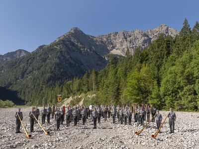 Musiker in Uniform vor Bergkulisse.