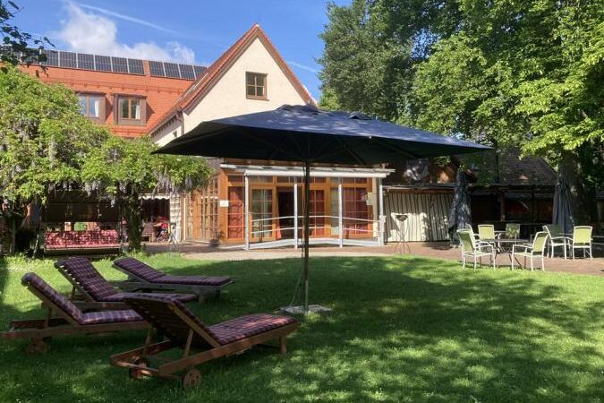 Gartenansicht auf das Caritashaus St. Elisabeth mit Liegestühlen im Vordergrund.