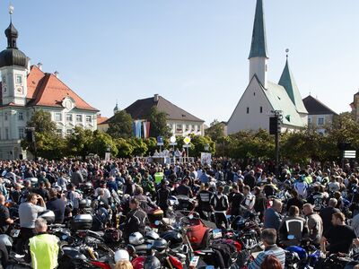 Viele Motorradfahrer stehen auf einem Platz.