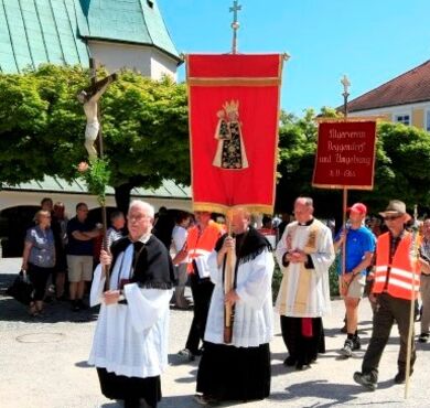 Die Geistlichkeit mit Fahnenträger führt einen Pilgereinzug am Kapellplatz Altötting an und zieht an der Gnadenkapelle vorbei. 