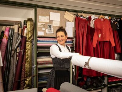 Eine Frau in Dirndl steht in einer Dirndlschneiderei. 