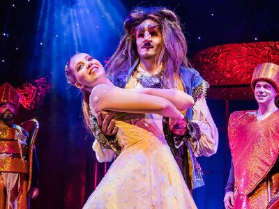 Ein Mädchen im Ballkleid tanzt mit einem Mann in furcheinfloessender Maske.