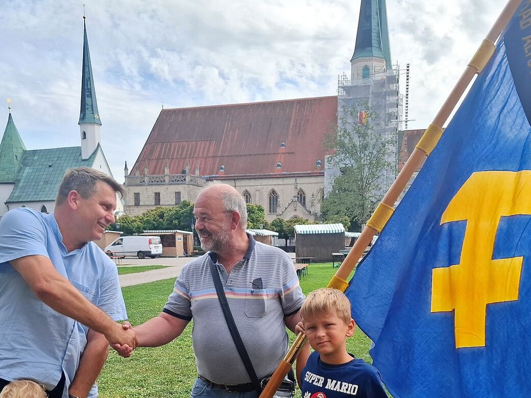 KAB, Jubilaeum, 2026, Peter Becker, Martin Antwerpen geben sich die Hand, Bild Monika Wagmann Peter Becker und Martin Antwerpen reichen sich die Hand und haben die Fahne der KAB in der Hand