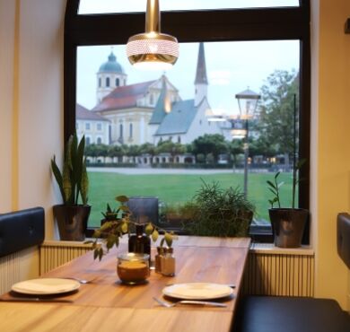 Sie sehen einen Tisch im Münchner Hof mit Aussicht auf den Kapellplatz.