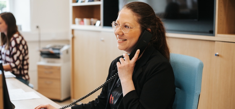 Eine Frau ist am Telefon und lächelt. 