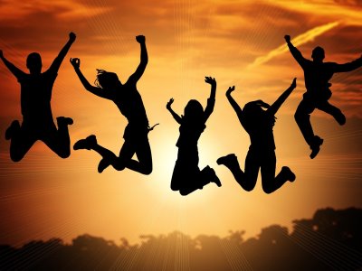 Junge Menschen hüpfen vor Freude in die Luft. 