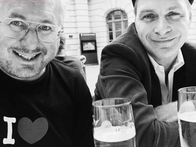Die beiden Autoren Oliver Pötzsch und Moses Wolff sitzen an einem Tisch mit zwei Gläsern Bier vor sich.