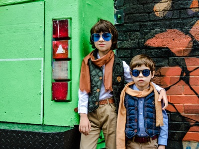 Zwei kleine Jungen mit stylischen Sonnenbrillen lehnen an einem alten Bus.