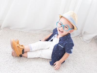 Ein kleiner Junge mit stylischem Hut und blauer übergroßer Sonnenbrille.