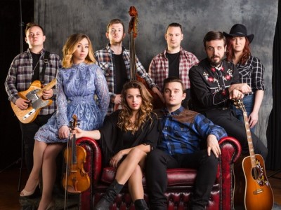 Eine Gruppe von Musikern mit Country Kleidung sitzen auf einer Couch.