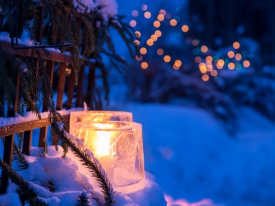 Kerzen stehen in einer schneebedeckten Landschaft.