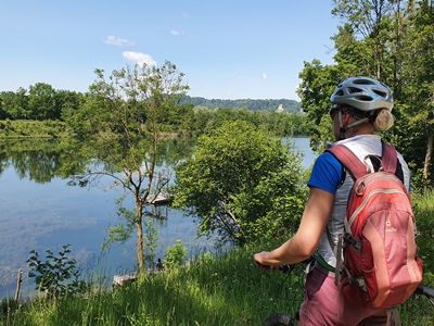 Radltour Burg und Badehose Altötting, Foto Touristinfo Altötting Eine Fahrradfahrerin blickt auf einen See.