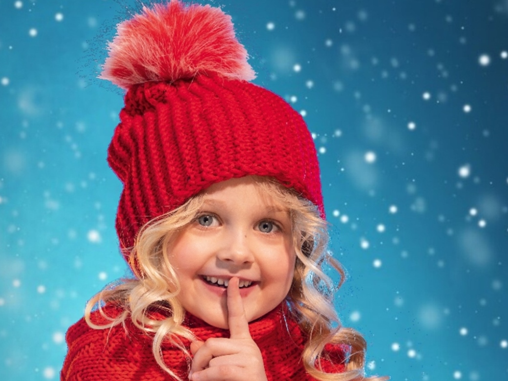 Ein kleines Mädchen hält ihren Finger vor den Mund und macht „pssst“. 