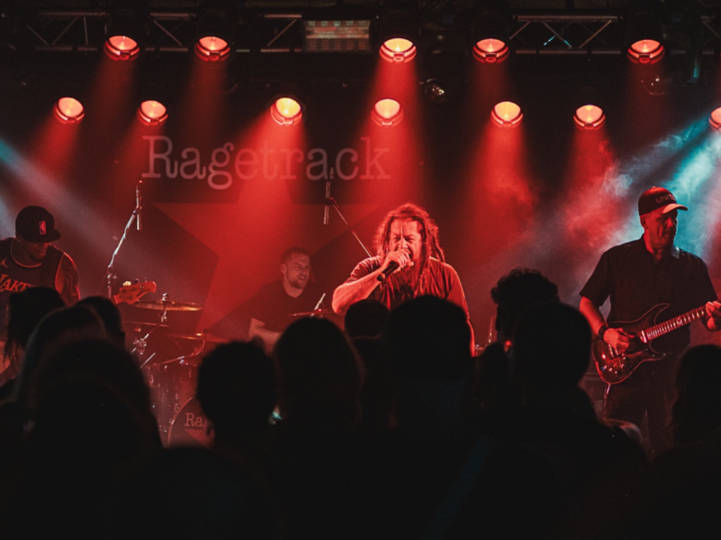 Ragetrack, Rage against the Machine, Forum, Altötting, Bild Jasmin Bailer Band auf einer Bühne mit rotem Bühnenlicht.