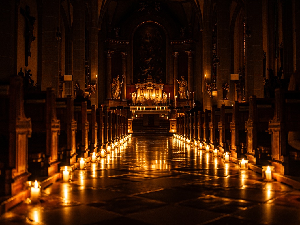 Vom Tod zum Leben, Transitus, Fest der Sinne, Altoetting, Bild Tom Bauer Ein Mittelgang in der einer Kirche nur mit Kerzen beleuchtet.
