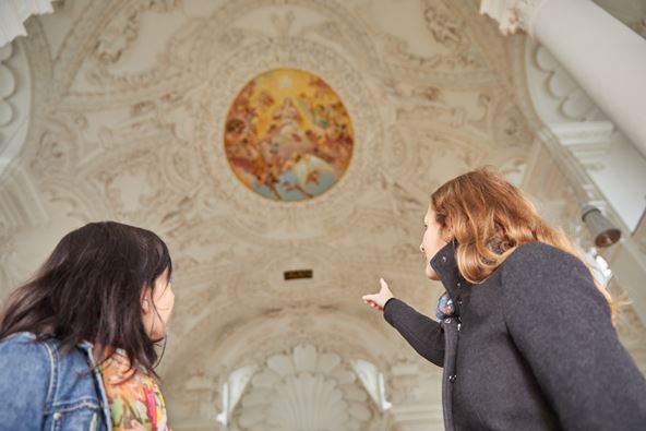 Zwei Frauen betrachten die Stuckdecke der Magdalena Kirche