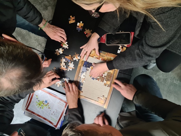 Vier Personen puzzeln gemeinsam ein Puzzle. 