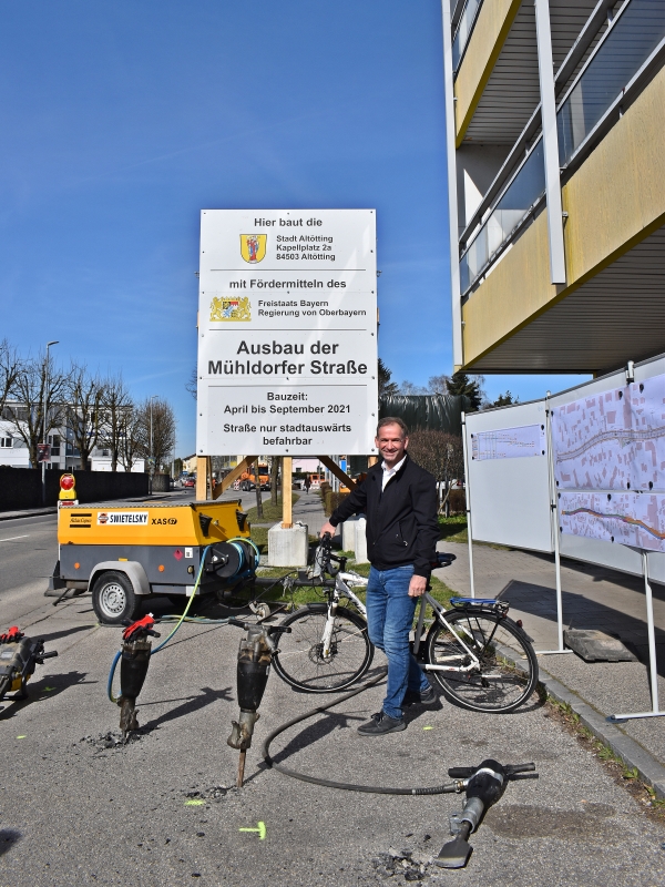 Hier sehen Sie Ersten Bürgermeister Stephan Antwerpen vor der Bautafeln für den Ausbau der Mühldorfer Straße in Altötting.
