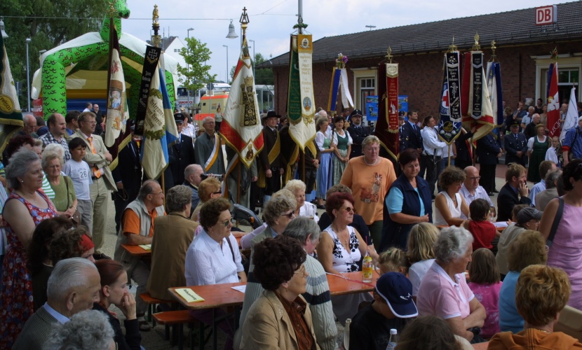 Bei dem Bahnhofsfest 2005 in Altötting sitzen die Menschen auf Bierbänken und hören den Reden zu.