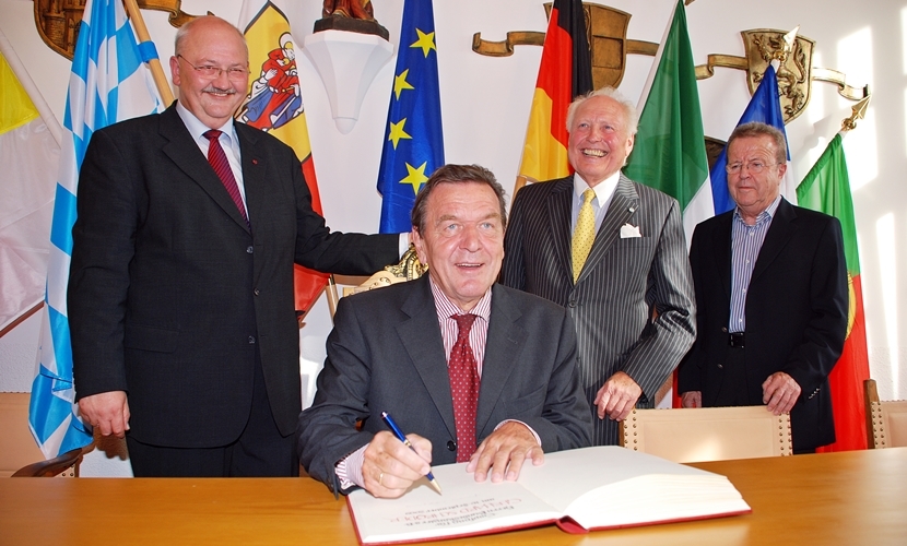 Der Altöttinger Bürgermeister steht neben Bundeskanzler a. D. Gerhard Schröder, als er in einem Buch unterschreibt.