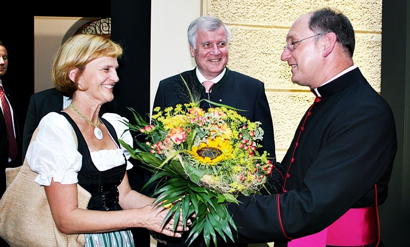 Ein Geistlicher überreicht einer Damen einen Blumenstrauß.