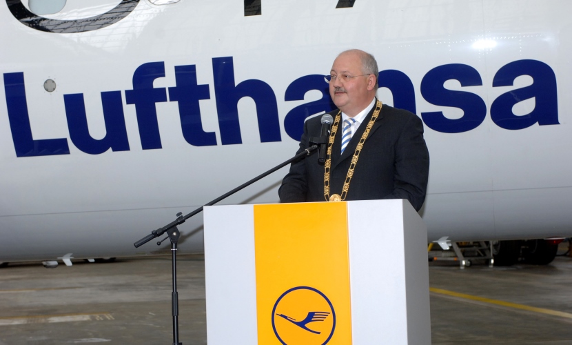 Bürgermeister Hofauer hält vor einem Flugzeug eine Rede.
