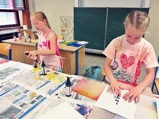 Kinder gestalten T-Shirts und bemalen und bedrucken diese.