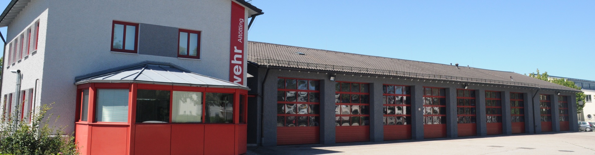 Gebäude der Feuerwehr Altötting mit parkenden Feuerwehrautos in der Garage.
