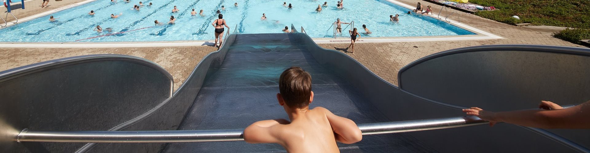 Ein Junge ist auf der Rutsche im Freibad Altötting.