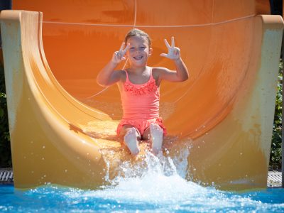 Ein Mädchen rutsch die Großrutsche im Freibad St. Georgen herunter.