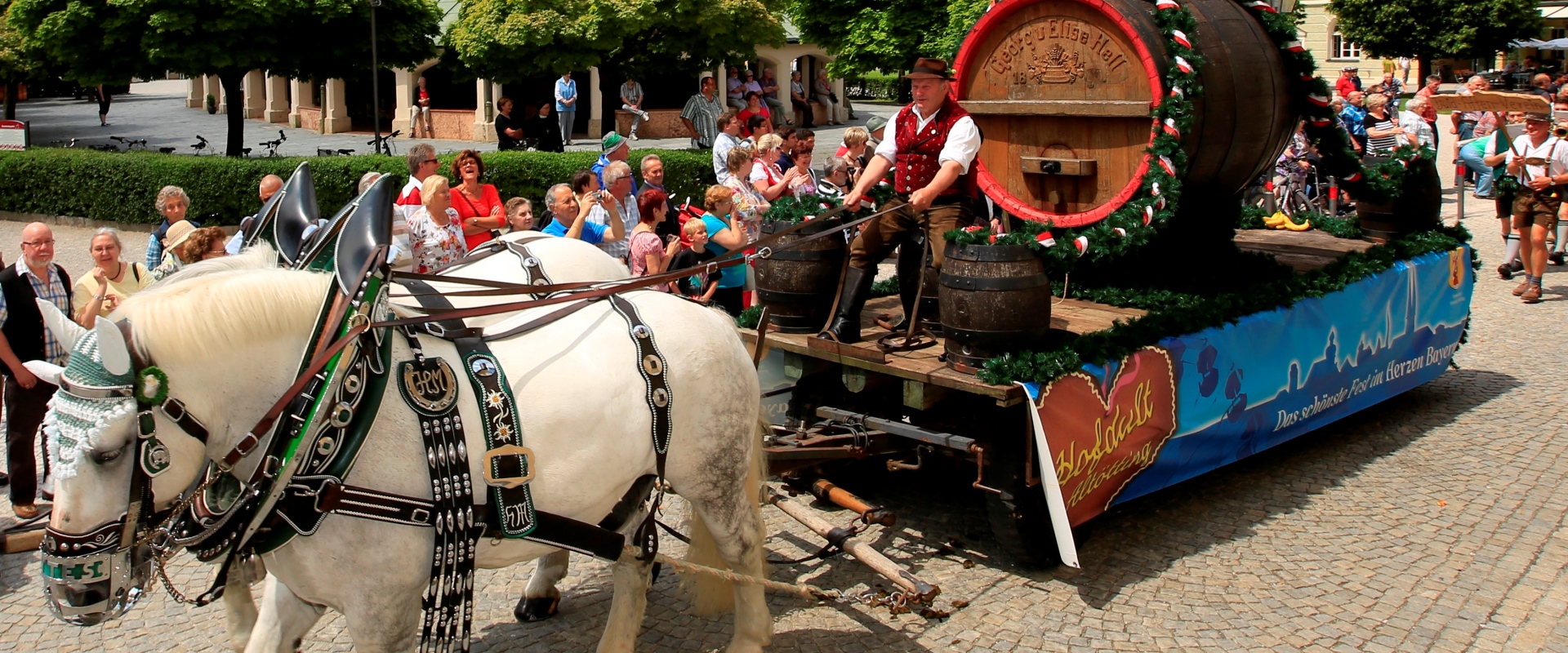 Zwei Pferde ziehen zum Hofdultauszug einen Wagen mit einem großen Bierfass.