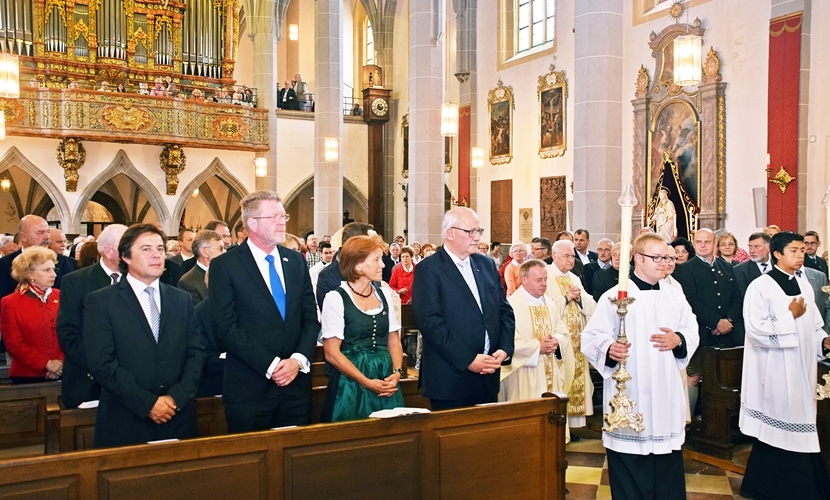Ehrengäste stehen in der Kirche während des Gottesdienstes, die Geistlichkeit zieht zwischen den Bänken zum Altar. 